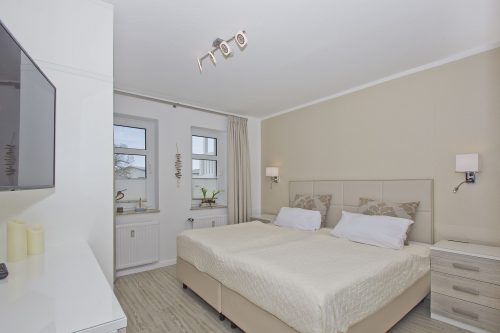 Schlafzimmer mit Boxspringbett und großem Fernseher